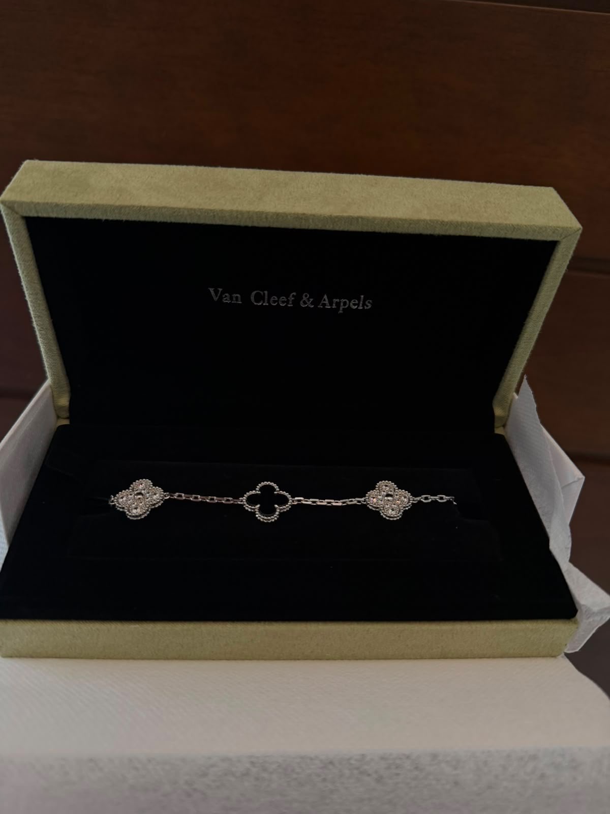 Pulsera con motivos de trébol en negro y engaste brillante, dentro de su estuche.